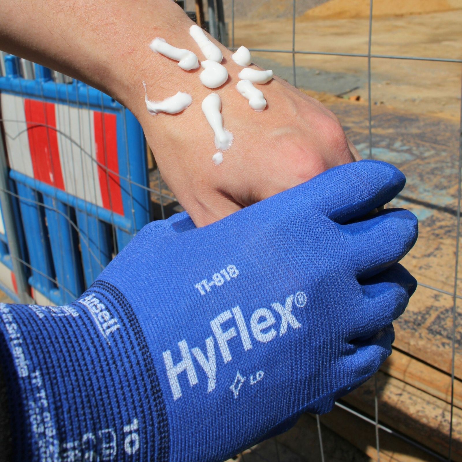 Handschutz im Sommer - Bild von einer Hand mit einer mit Sonnenmilch dargestellten Sonnen auf dem Handrücken und einer anderen Hand mit dem HyFlex 11-818